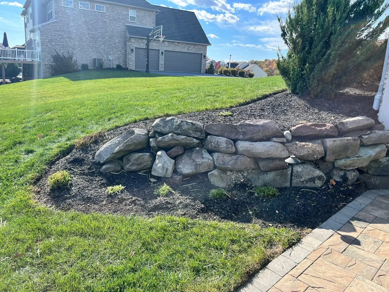 River rock border installation along fence line landscaping